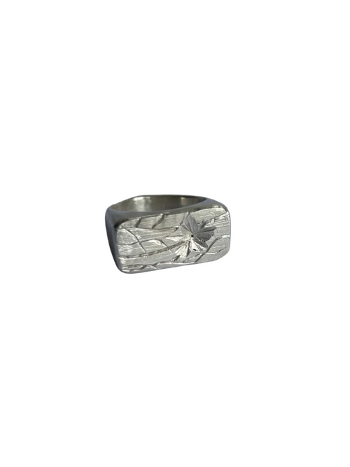 A silver textured ring with a wide, blocky band and a hammered, engraved silver surface with flower pattern 